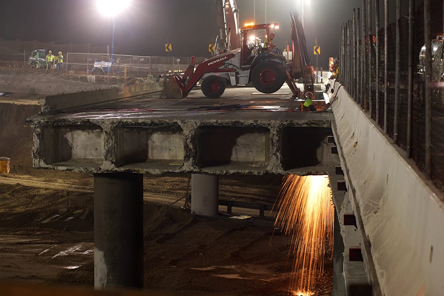 Looking east, sparks can be seen from the span over the I-405’s northbound lanes. Sparks result from a worker cutting steel reinforcements (rebar) under the bridge deck. Photo by Josh Southwick.