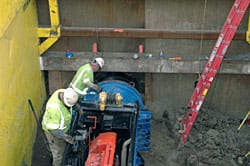 Workers use a diesel engine mounted on a short track to extract another auger from the new tunnel under Wilshire Bl.