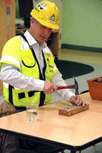 Kulka recreates pile driving on a small scale. He used the glass of water to illustrate how pounding creates vibration.