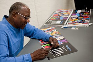 Artist signs first-edition prints of the Compton poster at the Compton Library program.