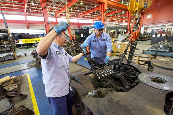 Fuyuong Chung, at right, and Josue Moir prepare to lift a Power Truck for installation on a Light Rail Vehicle