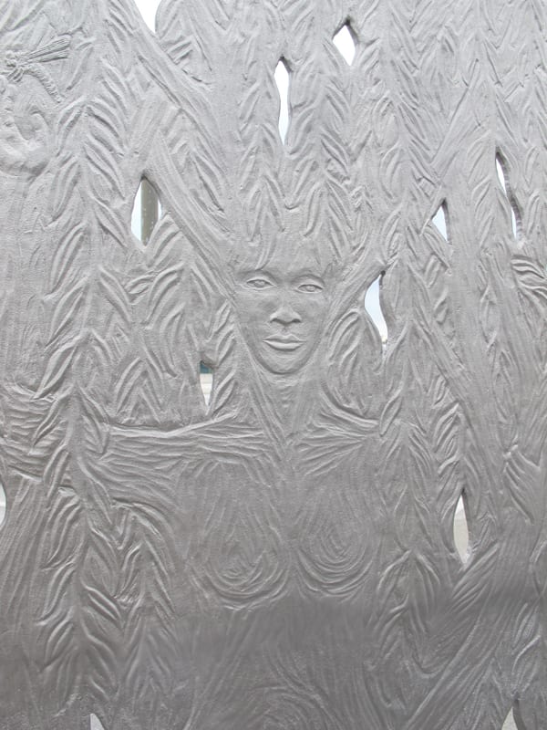 Detail of Paraje. The sculpture’s west face depicts a willow tree, while on the east face a willow spirit emerges mysteriously from the tree. The folds of the willow spirit’s dress become the roots of the tree and the spirit’s upheld arms become branches.