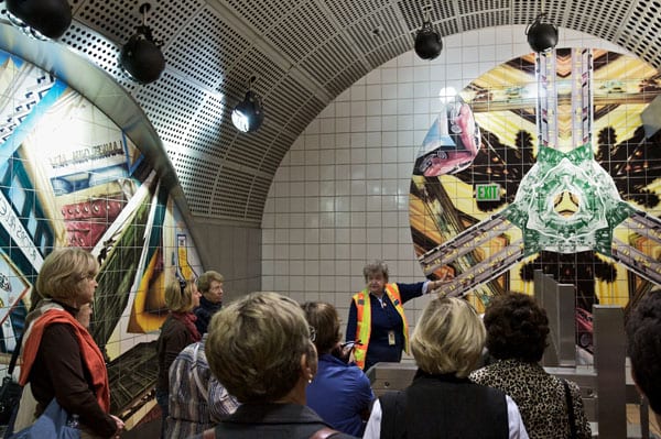 A Metro Art tour guide discusses the artwork at North Hollywood Station. The ceramic mural by Anne Marie Karlsen, called Kaleidoscope Dreams, depicts the dreams and aspirations of generations of San Fernando Valley immigrants and celebrates the Valley’s spirit and history.