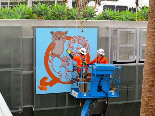 Phung Huynh's artwork being installed. Each artist created artwork in the medium of their choice, including drawing, painting and collage. This work was digitally captured in high-resolution digital files. The artwork was then translated onto 8’ x 8’ powder-coated aluminum panels, which can withstand the elements over the long-term, and are easy for Metro to maintain.