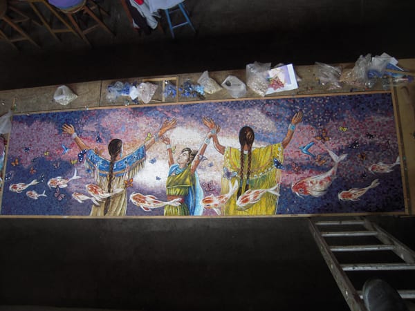 A view from above of an artwork panel completed by artisans who hand assembled thousands of mosaic pieces and pictured in nearby bags. Photo courtesy Perdomo Studio.