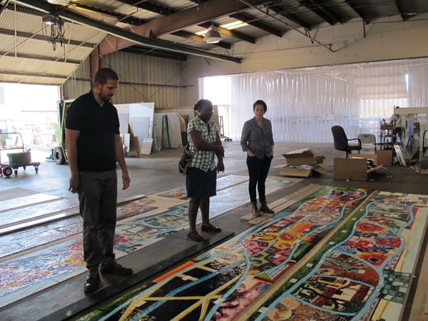 Nzuji de Magalhaes inspecting her artwork with Metro Art staff after they were delivered by the artwork fabricator to ensure that the original artworks are accurately reflected, and that the color is consistent among all eight of the panels.