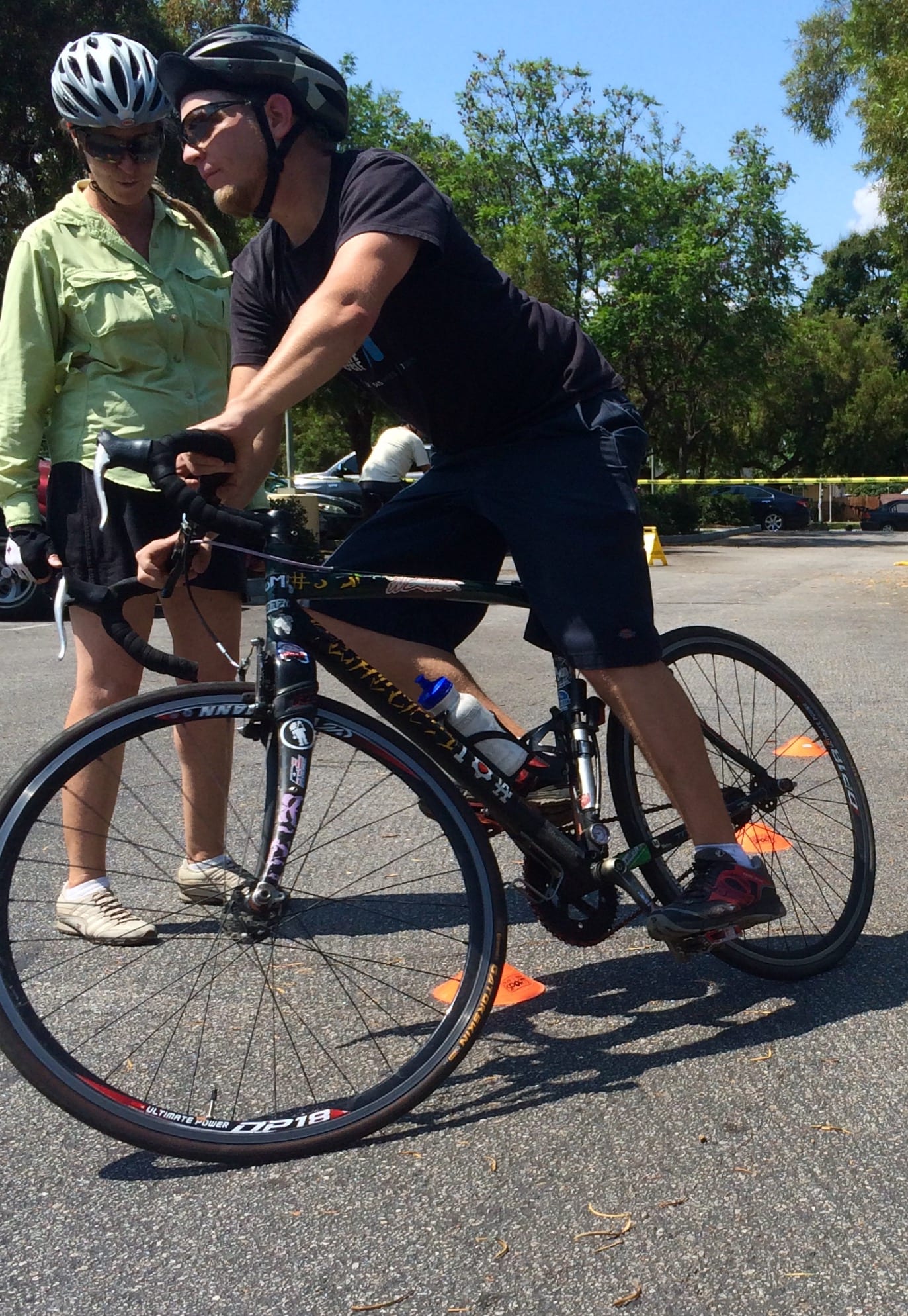 A safety instructor teaches bicycle maneuvering skills on road course.