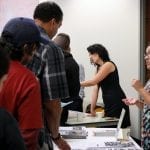 Jackie Cornejo, of LAANE, passes out "Your Path to a Construction Career" materials to residents. Photo by Ashley Thomas/LAANE