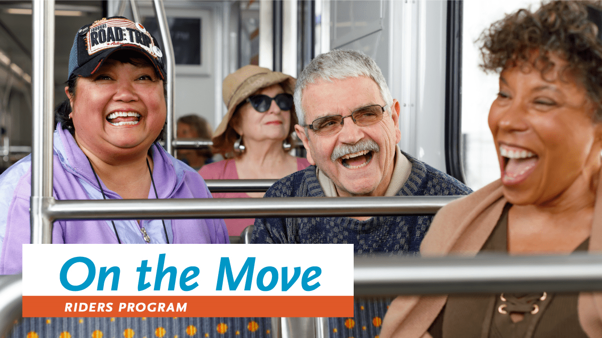 photo of smiling older adults together on a train. There is a black woman in the forefront, a latino woman wearing a baseball cap and white man wearing glasses behind her, and a white woman in a straw sunhat and sunglasses in the third row.