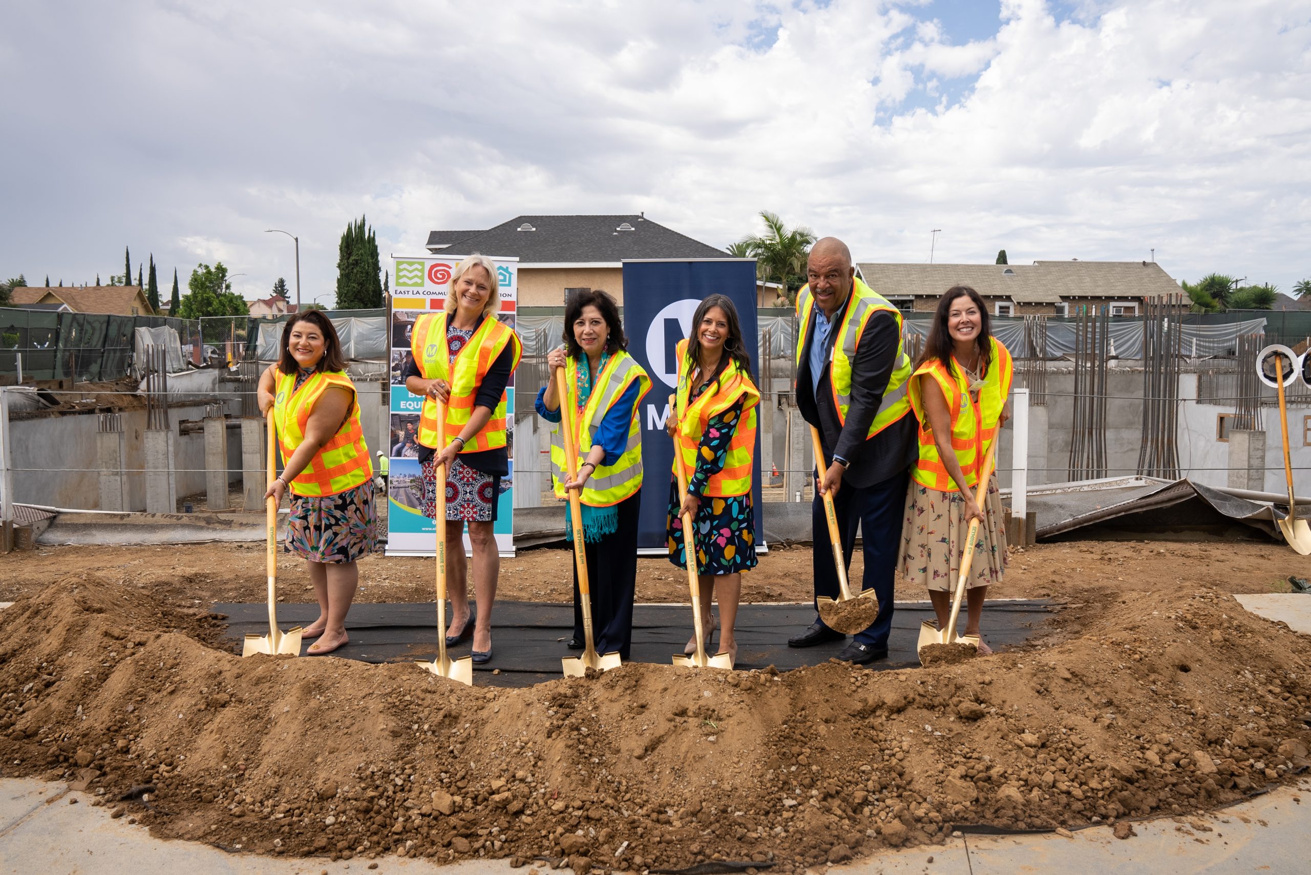 supervisor and metro board chair solis and officials hold shovels over a mound of dirt with the 1st and soto joint development construction site in the background